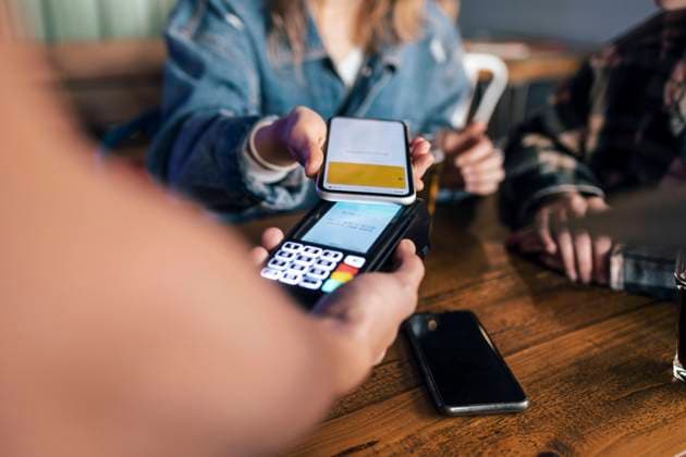 Young woman paying bill through smart phone at restaurant model released, Symbolfoto property released, JSRF02209