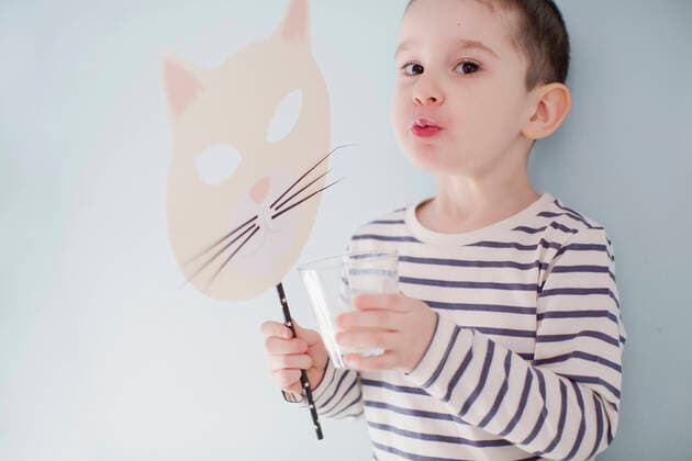 Creative Highlights Symbolbilder Boy drinking glass of milk and holding mask by wall model released, Symbolfoto, ONAF00006