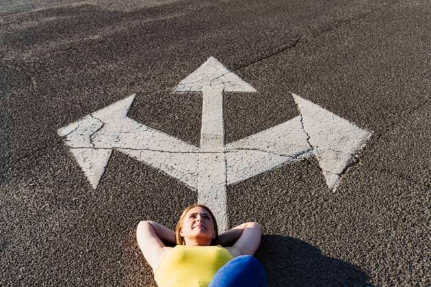 Carefree woman lying down near three way direction arrow sign on road model released, Symbolfoto, OSF00820
