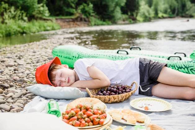 Boy sleeping on picnic blanket by cherry basket at riverbank model released, Symbolfoto, VBUF00138