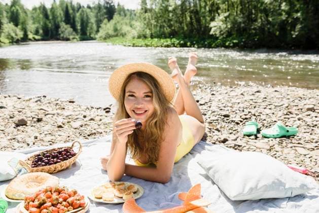 Woman holding cherry lying on blanket at riverbank model released, Symbolfoto, VBUF00150