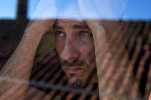 Depressed man sitting with head in hands seen through glass model released, Symbolfoto property released, VEGF05846