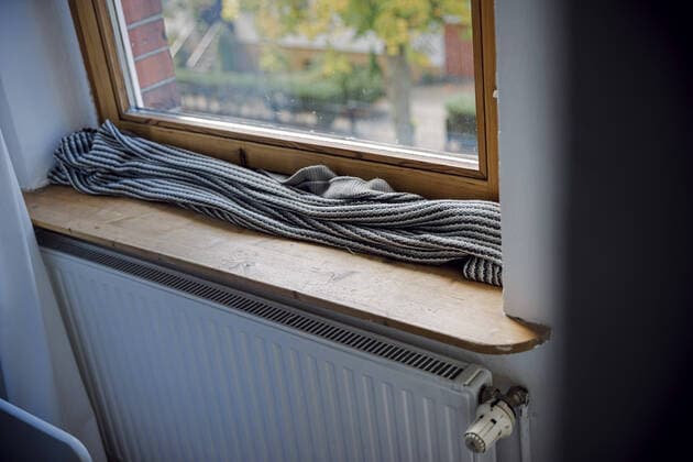 Symbolfoto zum Thema kalte Wohnung. Eine Decke liegt zum Schutz gegen kalte Luft auf der Fensterbank vor einem schlecht isolierten Fenster. Berlin, 29.09.2022 Berlin Deutschland *** Cold apartment symbol photo A blanket lies on the windowsill in front of a poorly insulated window to protect against cold air Berlin, 29 09 2022 Berlin Germany Copyright: xThomasxTrutschel photothek.dex