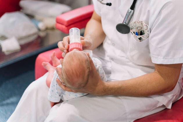 IMAGO Creative: Lokalhelden - Gesundheits- und Rettungskr?fte Doctors sitting on armchairs and feeding newborns from bottles holding heads in room with equipment in hospital, Model released JoseLuisCarrascosa_NewbornHospital_76 Copyright: xJosexLuisxCarrascosax MR