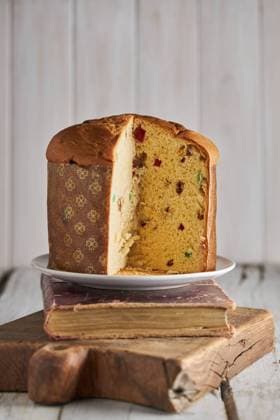 Still life of sliced fresh baked artisan Christmas panettone cake on vintage book and cutting board against light background RamonLopez_ID1110_42175_019 Copyright: xRamonxLopezx Model Released