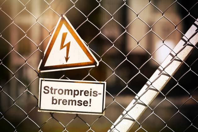 FOTOMONTAGE, Schild mit Strompfeil und der Aufschrift Strompreisbremse *** PHOTOMONTAGE, sign with electricity arrow and the inscription electricity price brake ** NUR FUER REDAKTIONELLE ZWECKE ** EDITORIAL USE ONLY **