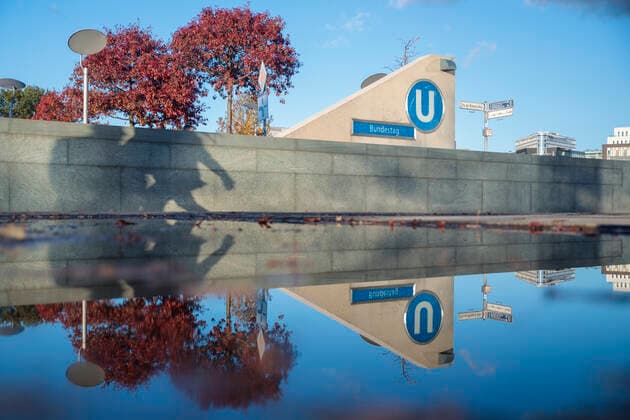 Symbolbild U-Bahn Bundestag im Herbst Deutschland, Berlin am 19.10.2022: Reflektionsbild durch gestautes Regenwasser: Vorplatz der neuen U-Bahn-Station Bundestag U5 im Sonnenschein, blauer Himmel und herbstlich belaubte Bäume, Schatten von zwei Passanten an der Mauer . *** Symbolic image U Bahn Bundestag in autumn Germany, Berlin on 19 10 2022 reflection image by accumulated rainwater forecourt of the new U Bahn station Bundestag U5 in the sunshine, blue sky and autumnal leafy trees, shadow of two passers-by on the wall