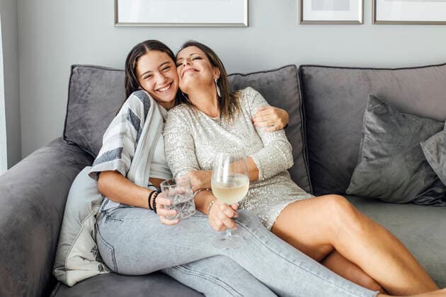 Smiling daughter embracing mother sitting on sofa at home model released, Symbolfoto property released, EGHF00568