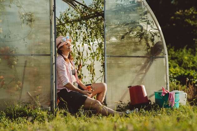 IMAGO Creative: Garten, Anbau im Gewächshaus Farmer with eyes closed holding tomatoes sitting at doorway of greenhouse model released, Symbolfoto property released, IEF00026