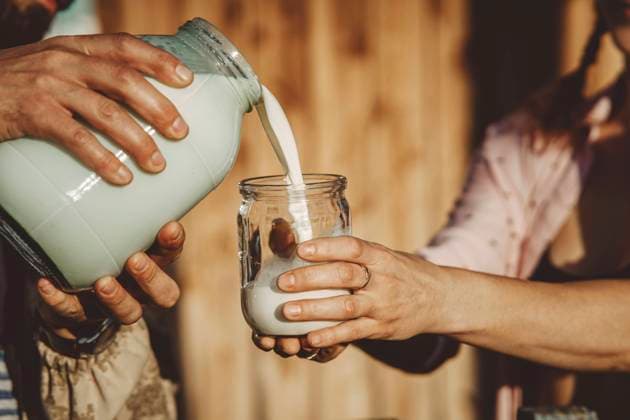 Man pouring fresh milk into glass jar on sunny day model released, Symbolfoto property released, IEF00168