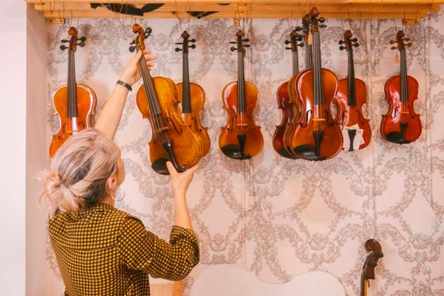 Luthier hanging violins in front of wall at store model released, Symbolfoto property released, MMPF00306
