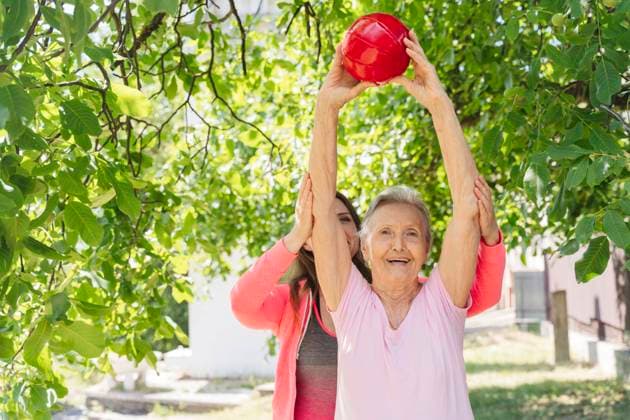 Happy senior woman with fitness instructor exercising in front of tree model released, Symbolfoto, OSF01009