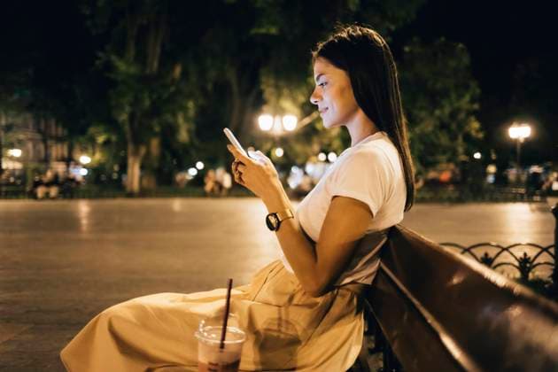 IMAGO Creative: Sommer, Sommertage im Stadtpark Woman using smart phone sitting on park bench at night model released, Symbolfoto, OYF00807
