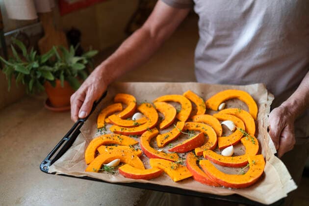 Hands of man showing pumpkin slices with thyme and garlic in tray at kitchen model released, Symbolfoto property released, SVKF00581