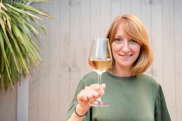 Smiling mature woman standing with glass of white wine in front of wall model released, Symbolfoto property released, SVKF00645