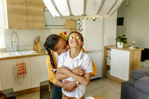 Mother embracing son covering eyes with cucumbers in kitchen model released, Symbolfoto property released, VIVF00025