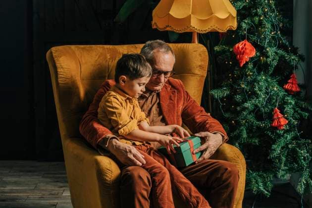 Grandson and grandfather sitting with gift box in armchair at home model released, Symbolfoto property released, VSNF00029