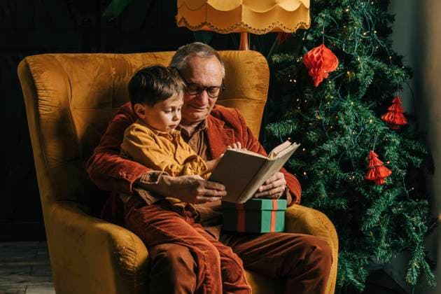 Smiling grandfather reading book to grandson at home model released, Symbolfoto property released, VSNF00030