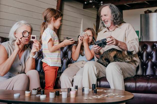 Granddaughters with grandparents looking at vintage film camera and film slides model released, Symbolfoto property released, YTF00154