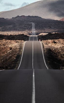 Endless road on a volcano in Timanfaya National Park in Lanzarote in the Canary Islands with a continuous line, black volcanic rocks on the side and volcanoes in mist in background. Endless road on a volcano in Timanfaya National Park in Lanzarote in the Canary Islands with a continuous line, black volcanic rocks on the side and volcanoes in mist in background. Copyright: xZoonar.com MatejxKastelicx 18342356