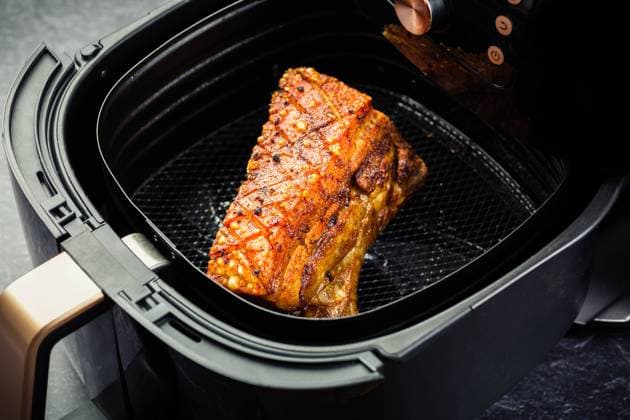 Cooking crispy pork belly in airfryer. Fast and easy crispy food cooking with little or no fat by circulating hot air inside the basket Cooking crispy pork belly in airfryer. Fast and easy crispy food cooking with little or no fat by circulating hot air inside the basket Copyright: xZoonar.com IngridxBalabanovax 18973482