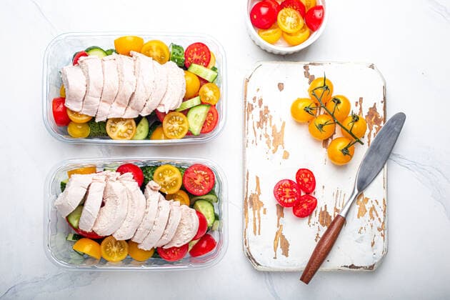 Meal prep lunch boxes containers with chicken and salad top view Healthy meal prep for lunch, diet boiled chicken fillet with vegetables salad in lunch boxes containers top view on white marble kitchen table background with knife and cutting board Copyright: xZoonar.com OlenaxYeromenkox 19104379