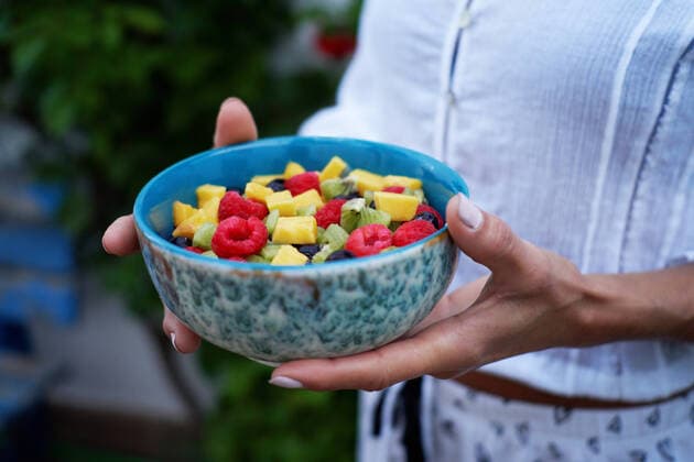 Soft focus of anonymous female demonstrating bowl of healthy fruit salad on summer day in yard, Model released CienXCienStudio_ID2267_72572_007 Copyright: xCienxXxCienxStudiox MR
