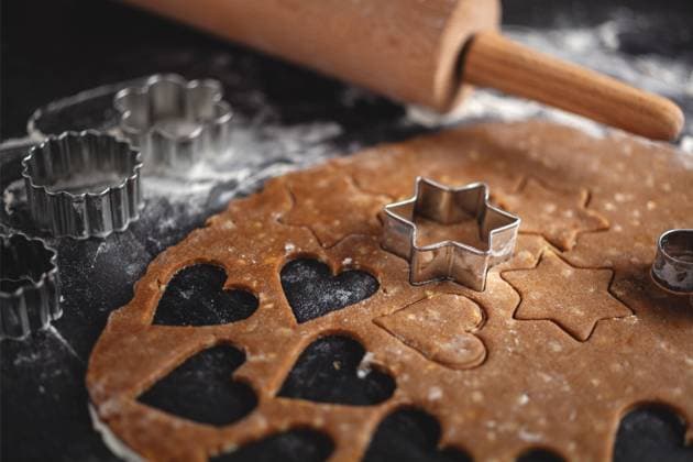 Plätzchen backen im Advent - aus Teig werden auf dunklem Untergrund weihnachtliche Motive für Lebkuchen ausgestochen - Deutschland *** Baking cookies in Advent Christmas motifs for gingerbread are cut out of dough on a dark background Germany