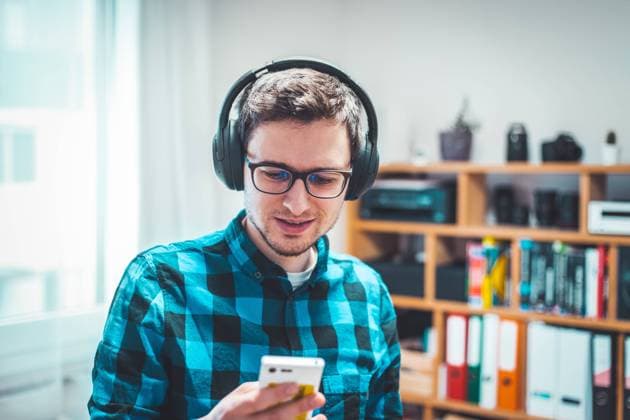 Enjoying music at home: Young Caucasian man is listening to music with headphones. Blue checked shirt. Young Caucasian man with checked blue shirt is listing to music with wireless headphones Copyright: xZoonar.com PatrickxDaxenbichlerx 15719115 ,model released, Symbolfoto ,property released