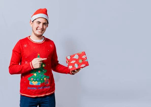  Lächelnder Typ mit Weihnachtsmütze, der eine Geschenkbox hält und darauf zeigt. Portrait eines Teenagers mit Weihnachtsmütze, der einen Geschenkkarton hält und darauf zeigt. Kerl in Weihnachtsmütze und Pullover hält eine Geschenkbox isoliert *** lächelnder Type with santa hat, the a Gift box holds and on it shows Portrait one Teenagers with santa hat, the a Gift box holds and on it shows Guy in Christmas cap and Sweaters holds a Gift box isolated Copyright: imageBROKER/IsaixHernandez ibxiih08834560.jpg ,model released, Symbolfoto ,property released