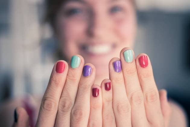 Pretty young woman with colorful nail polish. Smiling face in the blurry background. Close up picture of female fingers with colorful nail polish, face in the blurry background Copyright: xZoonar.com PatrickxDaxenbichlerx 16764619 ,model released, Symbolfoto ,property released