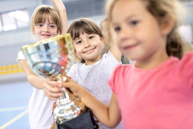 Schoolgirls celebrating victory with trophy at school sports court model released, Symbolfoto property released, WESTF25166