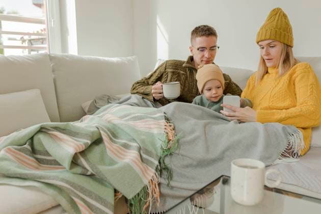 IMAGO Creative: Herbst, Gemütliches Zuhause Young couple with son using smart phone on sofa at home model released, Symbolfoto property released, VIVF00104
