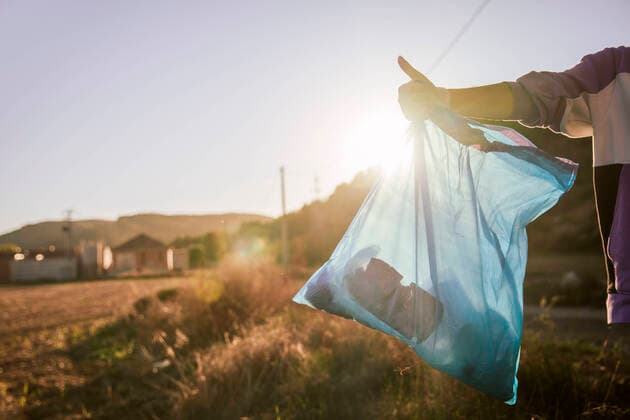 Woman holding garbage bag showing thumbs up gesture on sunset model released, Symbolfoto, ACPF01529