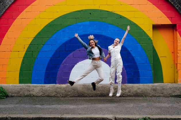 Happy lesbian couple jumping in front of rainbow painted wall model released, Symbolfoto, ASGF03061
