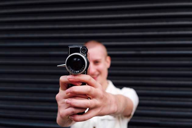 Non-binary person holding video camera in front of shutter model released, Symbolfoto, ASGF03094