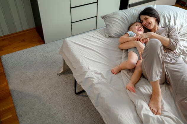 Creative Highlights Symbolbilder Happy woman playing with son in bed at home model released, Symbolfoto property released, ANAF00537