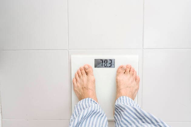 Man standing on weight scale at home model released, Symbolfoto property released, EYAF02319