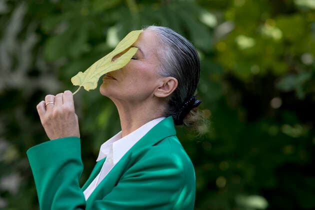 Creative Highlights Symbolbilder Senior woman with eyes closed holding fig leaf on face model released, Symbolfoto property released, FLLF00814