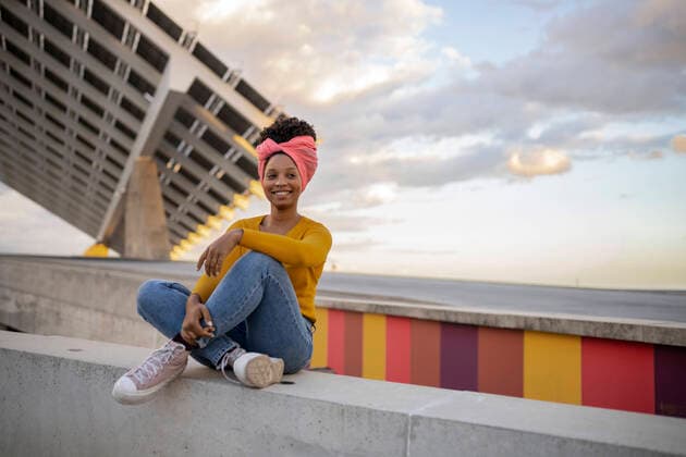 Creative Highlights Symbolbilder Happy young woman wearing headscarf sitting on wall in front of solar panels model released, Symbolfoto, JCCMF08017