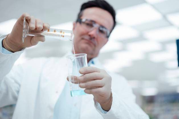 Chemist pouring solution from test tube to flask in laboratory model released, Symbolfoto property released, JOSEF14564
