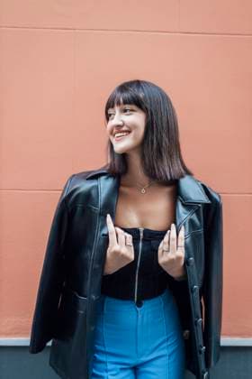 Fashion Trend Report 2023: Lederjacken 90er Stil Creative Highlights Symbolbilder Happy young woman wearing leather jacket in front of wall model released, Symbolfoto, JRVF03245