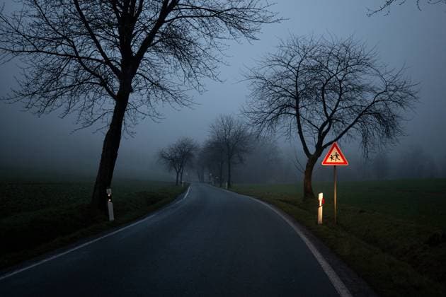 IMAGO Creative, Jahreszeit Herbst auf dem Land Eine von Bäumen gesäumte Landstraße im Nebel in der Abenddämmerung. Ein vom Sautoscheinwerfer angestrahltes Verkehrsschild welches vor Kindern warnt. *** a from Trees lined Country road at Fog in the Twilight a from car headlights Angestrahltes Traffic sign which before Children warns 1083402473