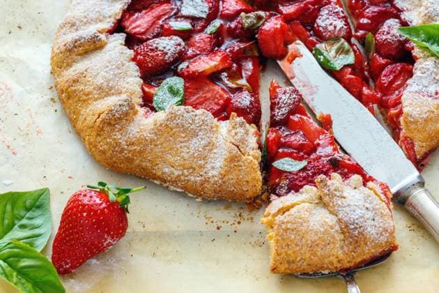 Cut homemade cake with strawberries and basil. Cut free-form cake with strawberries and basil sprinkled with powdered sugar on an old white table. Copyright: xZoonar.com MarinaxSaprunovax 12284027