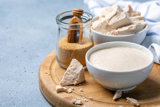 Pressed yeast, dry yeast and active sourdough starter. Dry instant yeast, fresh pressed yeast and active wheat sourdough starter on wooden board, selective focus. Copyright: xZoonar.com MarinaxSaprunovax 14589035