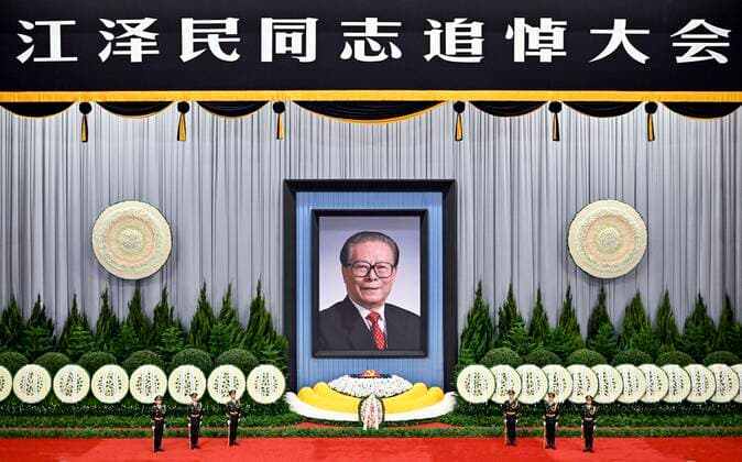 (221206) -- BEIJING, Dec. 6, 2022 -- A memorial meeting for Jiang Zemin, who passed away on Nov. 30 at the age of 96, is held in the Great Hall of the People in Beijing, capital of China, Dec. 6, 2022. The meeting was held by the Communist Party of China (CPC) Central Committee, the Standing Committee of the National People s Congress, the State Council, the National Committee of the Chinese People s Political Consultative Conference, and the Central Military Commission. Jiang s casket, covered with the flag of the CPC, was placed amidst bouquets of flowers and sprigs of evergreen cypress. A floral arrangement presented by family members of Jiang, including his wife Wang Yeping, was placed in front of the casket, flanked by six guards 