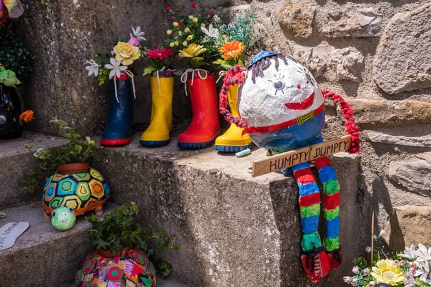 Colorful decoration with rubber shoes, flowers and a puppet at a house entrance Castel Rigone Umbria Italy Reise FB_2018_1627