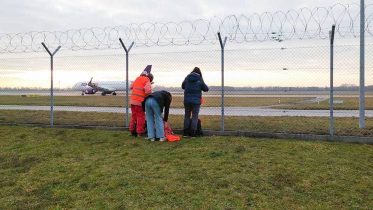 Letzte Generation demonstriert am Flughafen München Aktivist*innen der Letzten Generation demonstrierten am 8.12.2022 vor dem Stcheldrahtzaun des Münchner Flughafens für die Wiedereinführung des Neun-Euro-Ticket und ein Tempolimit von 100 km h auf deutschen Autobahnen. -- Activists of the Last Generation demonstrated on December 8, 2022, in front of the barbed wire fence of Munich Airport for the reintroduction of the 9-euro ticket and a speed limit of 100 km h on German highways. Flughafen München Bayern Deutschland Copyright: xLGPBx