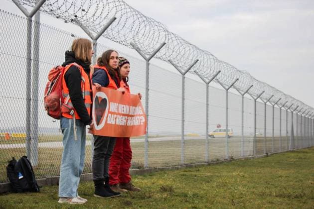 Letzte Generation demonstriert am Flughafen München Aktivist*innen der Letzten Generation demonstrierten am 8.12.2022 vor dem Stcheldrahtzaun des Münchner Flughafens und auf dem Rollfeld für die Wiedereinführung des Neun-Euro-Ticket und ein Tempolimit von 100 km h auf deutschen Autobahnen. -- Activists of the Last Generation demonstrated on December 8, 2022, in front of the barbed wire fence of Munich Airport and on the runway for the reintroduction of the 9-euro ticket and a speed limit of 100 km h on German highways. Flughafen München Bayern Deutschland Copyright: xLGPBx