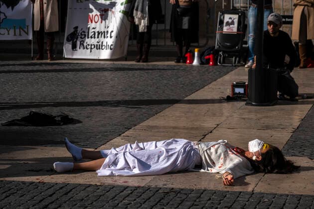 December 10, 2022, Barcelona, Catalonia, Spain: A woman stretched out on the ground of the Plaza de Sant Jaume covered in fake blood representing the repression of the Iranian regime seen during the demonstration. Coinciding with Human Rights Day, hundreds of demonstrators have demonstrated in the center of Barcelona to protest against the repression of the Iranian regime and against the death sentences of those detained during the demonstrations. Barcelona Spain - ZUMAs197 20221210_zaa_s197_147 Copyright: xPacoxFreirex